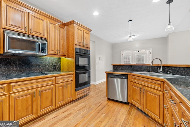 kitchen featuring light hardwood / wood-style flooring, black appliances, sink, decorative backsplash, and pendant lighting