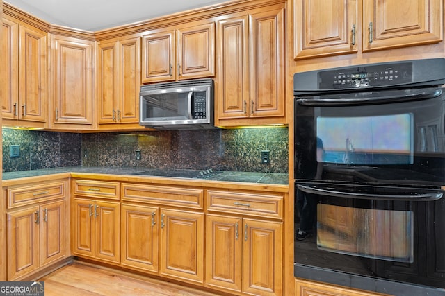 kitchen featuring light wood-type flooring, tile counters, black appliances, and backsplash