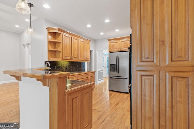 kitchen with light hardwood / wood-style flooring, hanging light fixtures, stainless steel fridge with ice dispenser, and kitchen peninsula