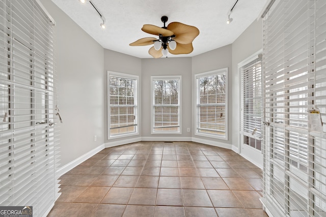 unfurnished sunroom with ceiling fan and track lighting