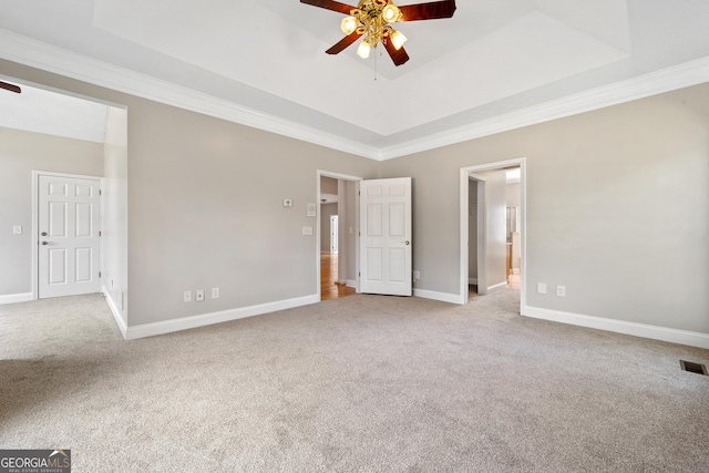 carpeted spare room with a raised ceiling, crown molding, and ceiling fan