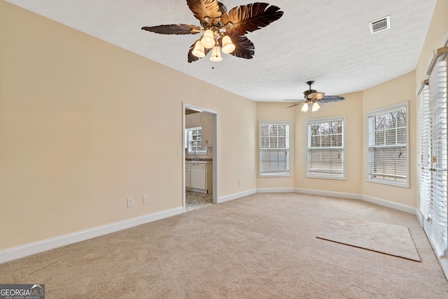 carpeted spare room featuring ceiling fan and a textured ceiling