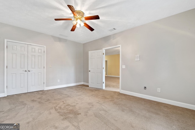 unfurnished bedroom with a closet, ceiling fan, carpet flooring, and a textured ceiling