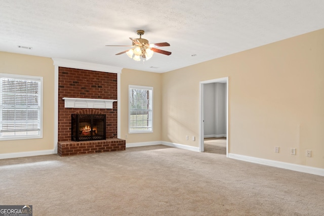 unfurnished living room featuring a fireplace, light carpet, a textured ceiling, and ceiling fan