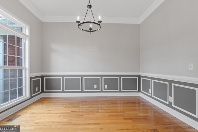 unfurnished dining area featuring ornamental molding, a notable chandelier, and light hardwood / wood-style flooring