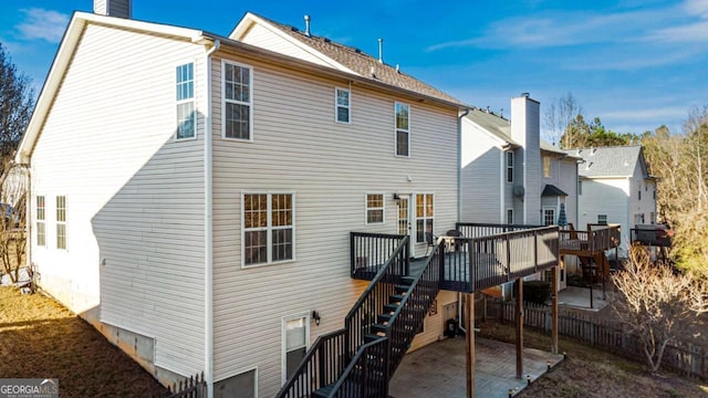 back of property with a wooden deck, a patio area, a chimney, and stairs