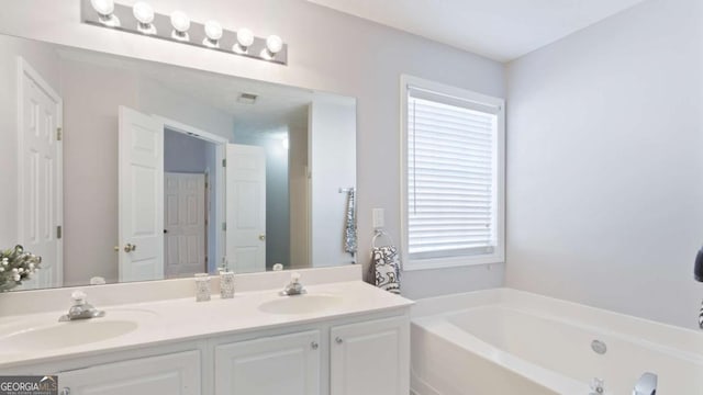 bathroom featuring a bath, visible vents, double vanity, and a sink