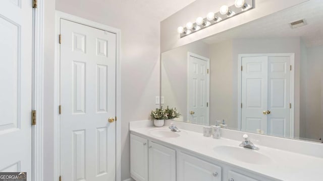 full bath with a sink, visible vents, and double vanity