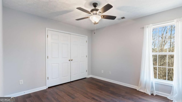 unfurnished bedroom featuring visible vents, baseboards, a textured ceiling, and dark wood-style flooring