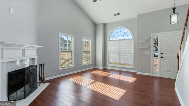 unfurnished living room with stairs, a fireplace, dark wood finished floors, and a wealth of natural light