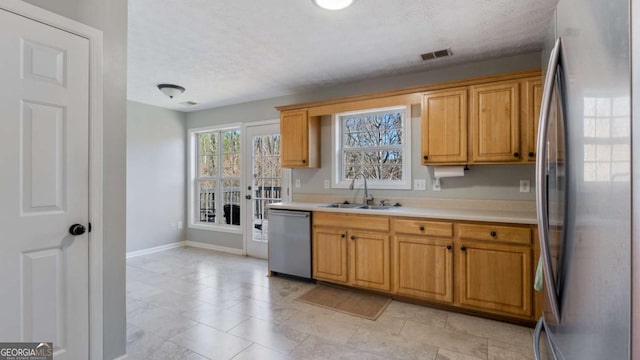 kitchen with baseboards, visible vents, a sink, stainless steel appliances, and light countertops