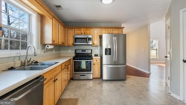 kitchen with visible vents, baseboards, light countertops, stainless steel appliances, and a sink