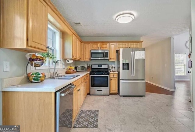 kitchen with visible vents, a sink, appliances with stainless steel finishes, light countertops, and baseboards