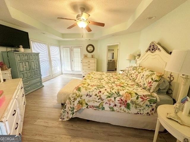 11 Plantation Dr, Swainsboro, GA 30401 - bedroom featuring ceiling fan, a textured ceiling, light wood-style flooring, access to exterior, and a raised ceiling