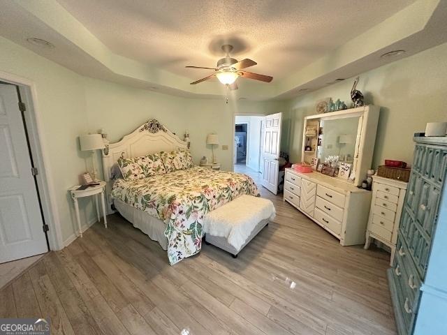 11 Plantation Dr, Swainsboro, GA 30401 - bedroom with baseboards, a raised ceiling, a ceiling fan, a textured ceiling, and light wood-type flooring