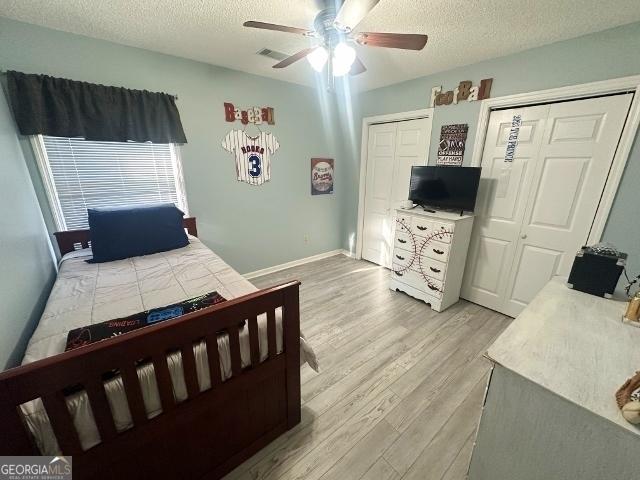11 Plantation Dr, Swainsboro, GA 30401 - bedroom with light wood-type flooring, two closets, visible vents, and a textured ceiling