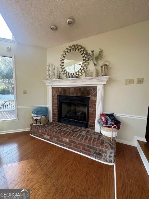 11 Plantation Dr, Swainsboro, GA 30401 - interior details featuring a textured ceiling, a fireplace, baseboards, and wood finished floors