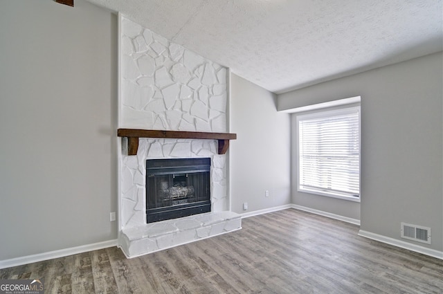 unfurnished living room featuring a fireplace, a textured ceiling, and hardwood / wood-style floors