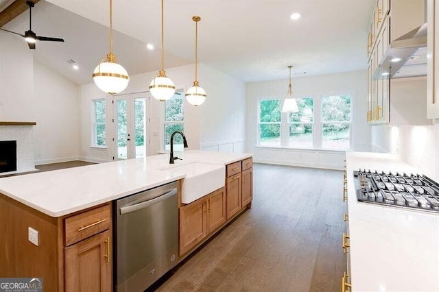 kitchen with a center island with sink, stainless steel appliances, pendant lighting, a fireplace, and sink