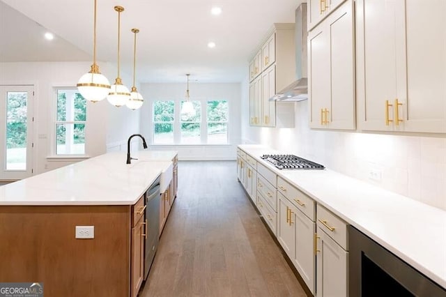 kitchen with beverage cooler, a large island with sink, pendant lighting, stainless steel appliances, and wall chimney exhaust hood