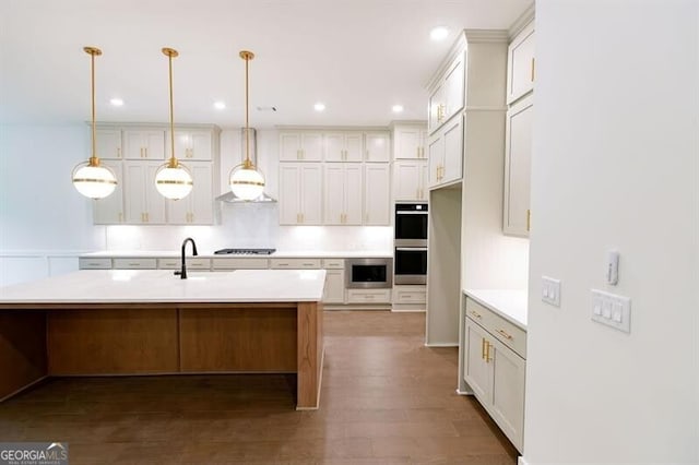 kitchen with pendant lighting, dark hardwood / wood-style floors, wall chimney range hood, stainless steel appliances, and a kitchen island with sink