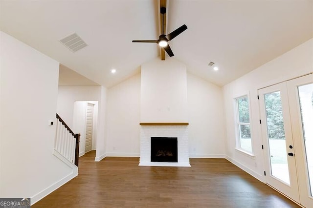 unfurnished living room featuring french doors, dark hardwood / wood-style floors, ceiling fan, a fireplace, and high vaulted ceiling