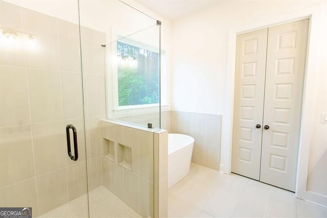 bathroom with shower with separate bathtub, tile patterned floors, and tile walls