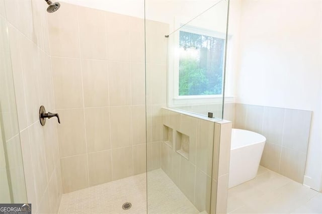 bathroom featuring shower with separate bathtub and tile walls