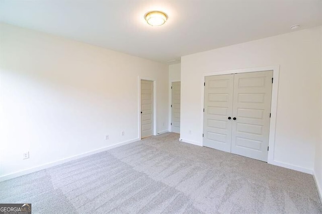 unfurnished bedroom with light carpet and a closet