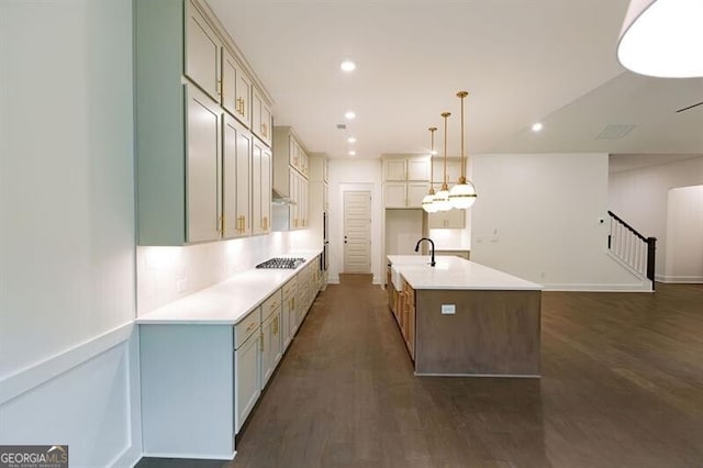 kitchen with stainless steel gas stovetop, dark hardwood / wood-style flooring, an island with sink, and pendant lighting