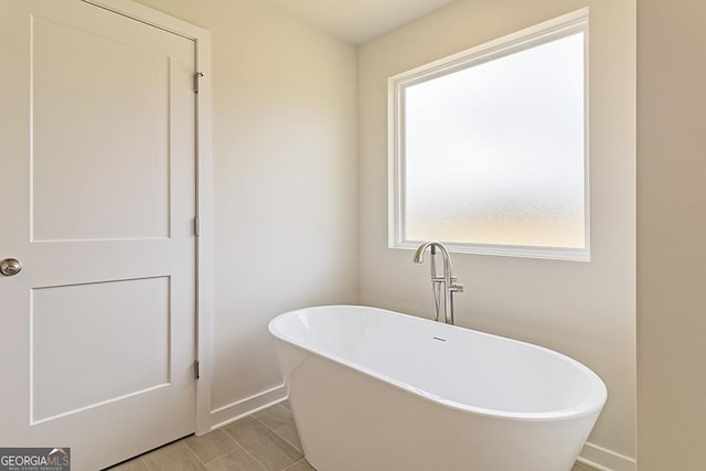 bathroom with a freestanding bath and baseboards