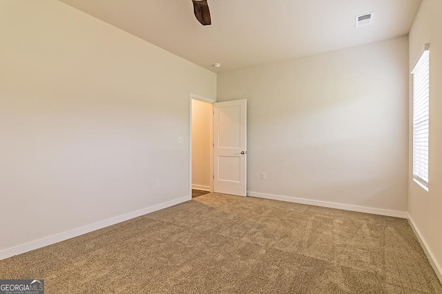 spare room featuring carpet floors, baseboards, visible vents, and a ceiling fan