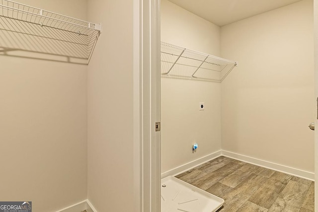 laundry room with laundry area, baseboards, electric dryer hookup, and wood finished floors