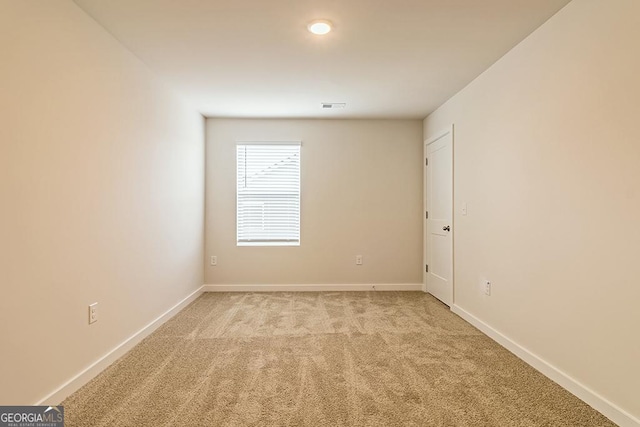 spare room featuring light carpet, visible vents, and baseboards