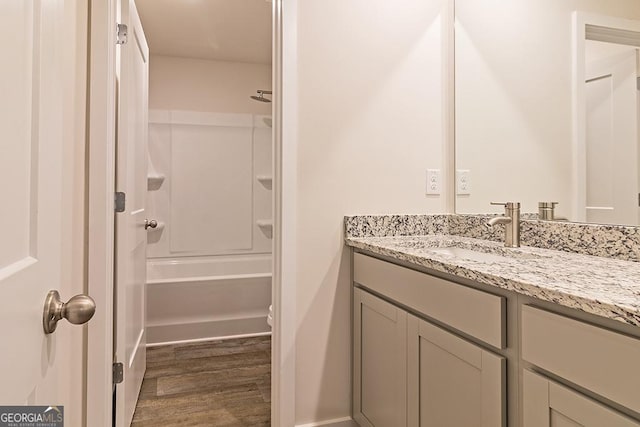 full bathroom featuring bathing tub / shower combination, baseboards, wood finished floors, and vanity