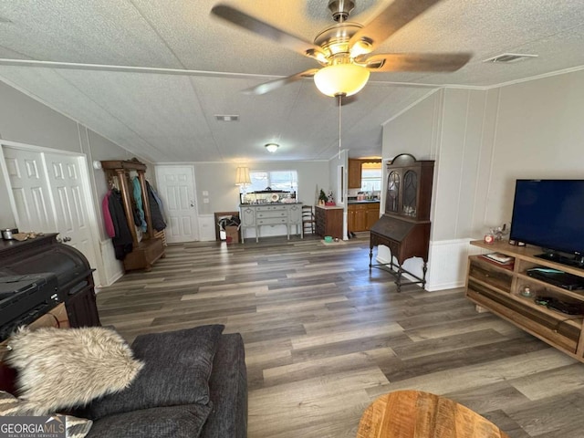 living room with crown molding, vaulted ceiling, dark wood-type flooring, and a textured ceiling