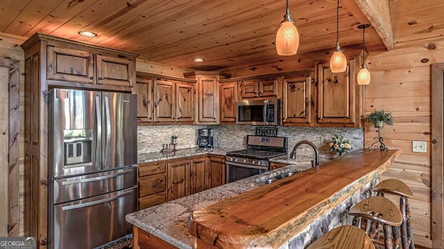 kitchen featuring appliances with stainless steel finishes, sink, dark stone counters, and kitchen peninsula