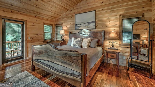 bedroom featuring hardwood / wood-style floors, multiple windows, vaulted ceiling, and wooden walls