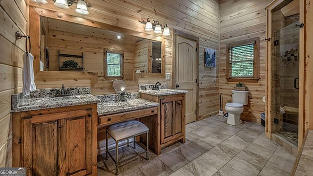 bathroom featuring a shower with shower door, vanity, wooden walls, and toilet