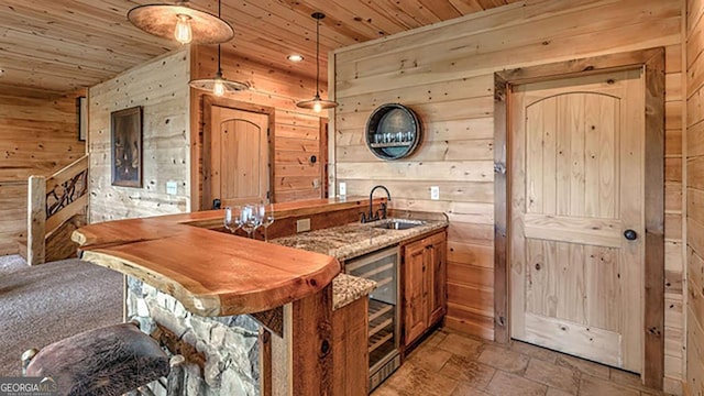 kitchen featuring hanging light fixtures, wood walls, sink, wooden ceiling, and beverage cooler