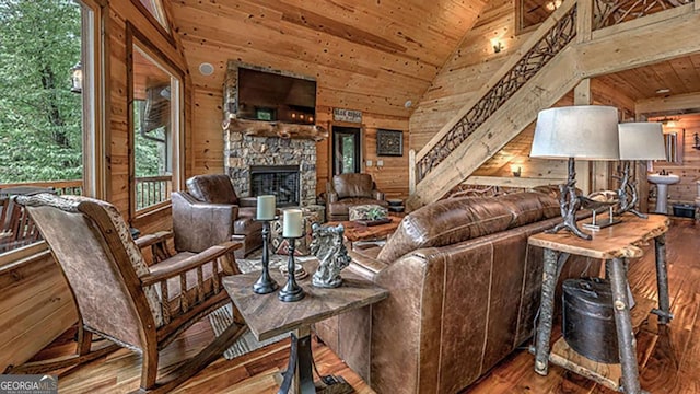 living room featuring wood ceiling, wood-type flooring, wood walls, and a stone fireplace