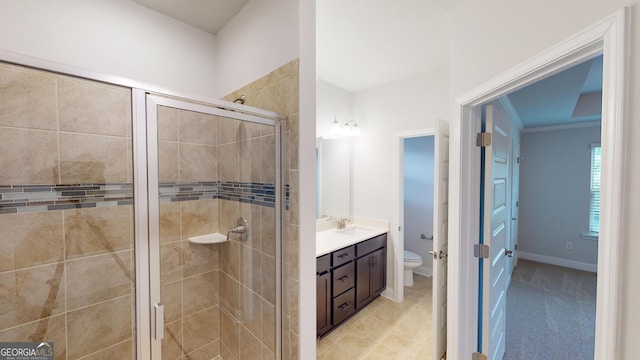 bathroom featuring toilet, ornamental molding, vanity, and a shower with door