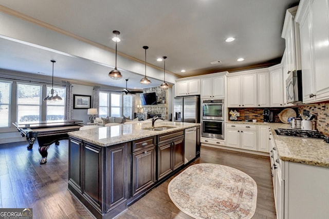 kitchen with a center island with sink, stainless steel appliances, white cabinets, pendant lighting, and sink