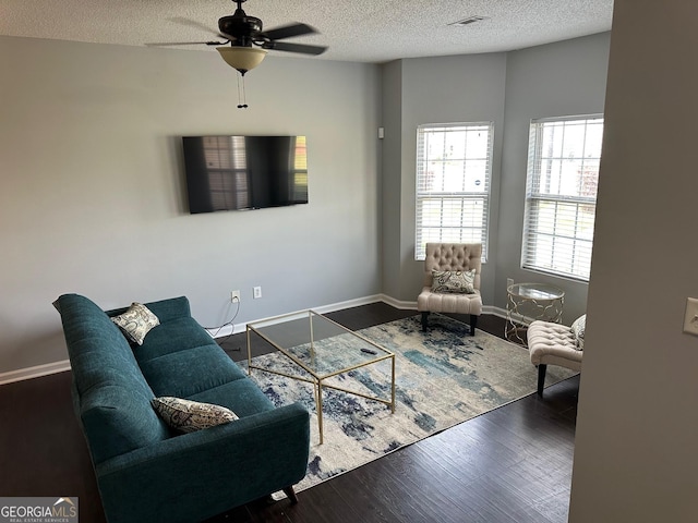 living room with dark hardwood / wood-style flooring, ceiling fan, and a textured ceiling