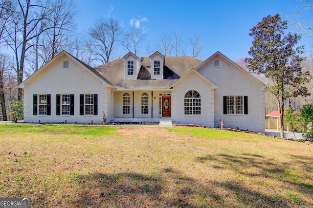 view of front of home featuring covered porch, brick siding, and a front yard