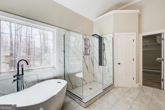 full bath featuring lofted ceiling, a freestanding bath, a marble finish shower, tile patterned floors, and crown molding