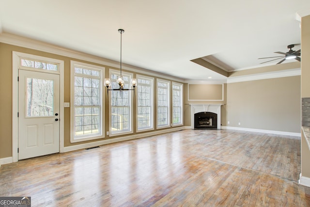 unfurnished living room with a fireplace, crown molding, visible vents, wood finished floors, and baseboards