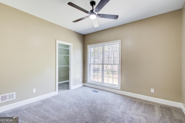 carpeted spare room featuring ceiling fan, visible vents, and baseboards