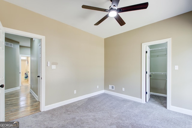 unfurnished bedroom with carpet flooring, a walk in closet, visible vents, and baseboards