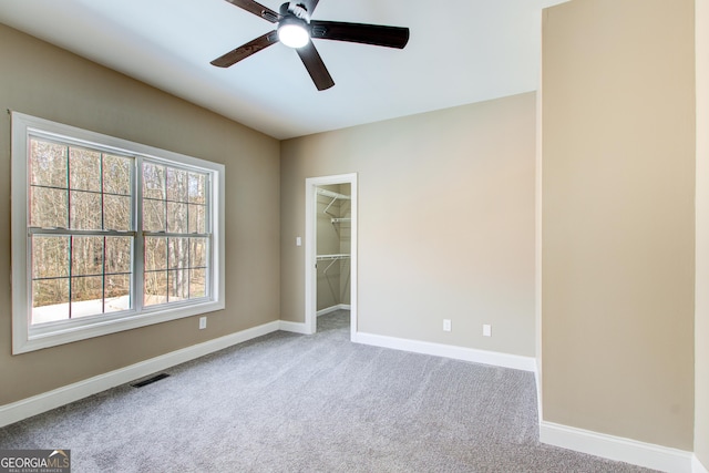 carpeted spare room featuring a ceiling fan, visible vents, and baseboards